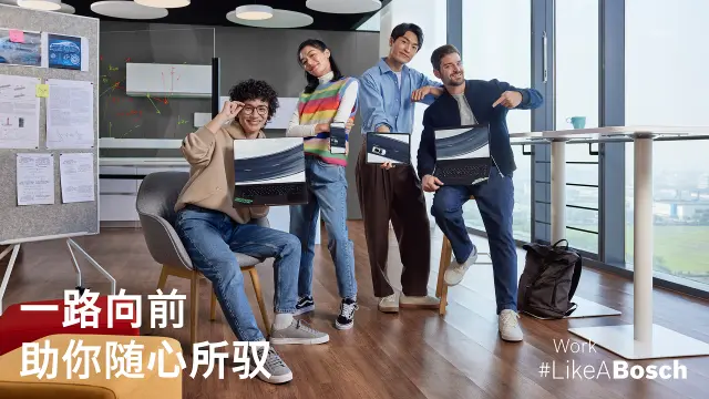 一名员工在展示架前摆姿势拍照，展示架上摆满了印有welcometo欢迎光临888集团相关图案的帽子，例如“Work #LikeABosch”主题。